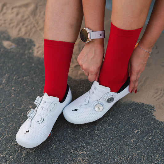 Rider puts shoes on with Veto's bold red cycling socks 